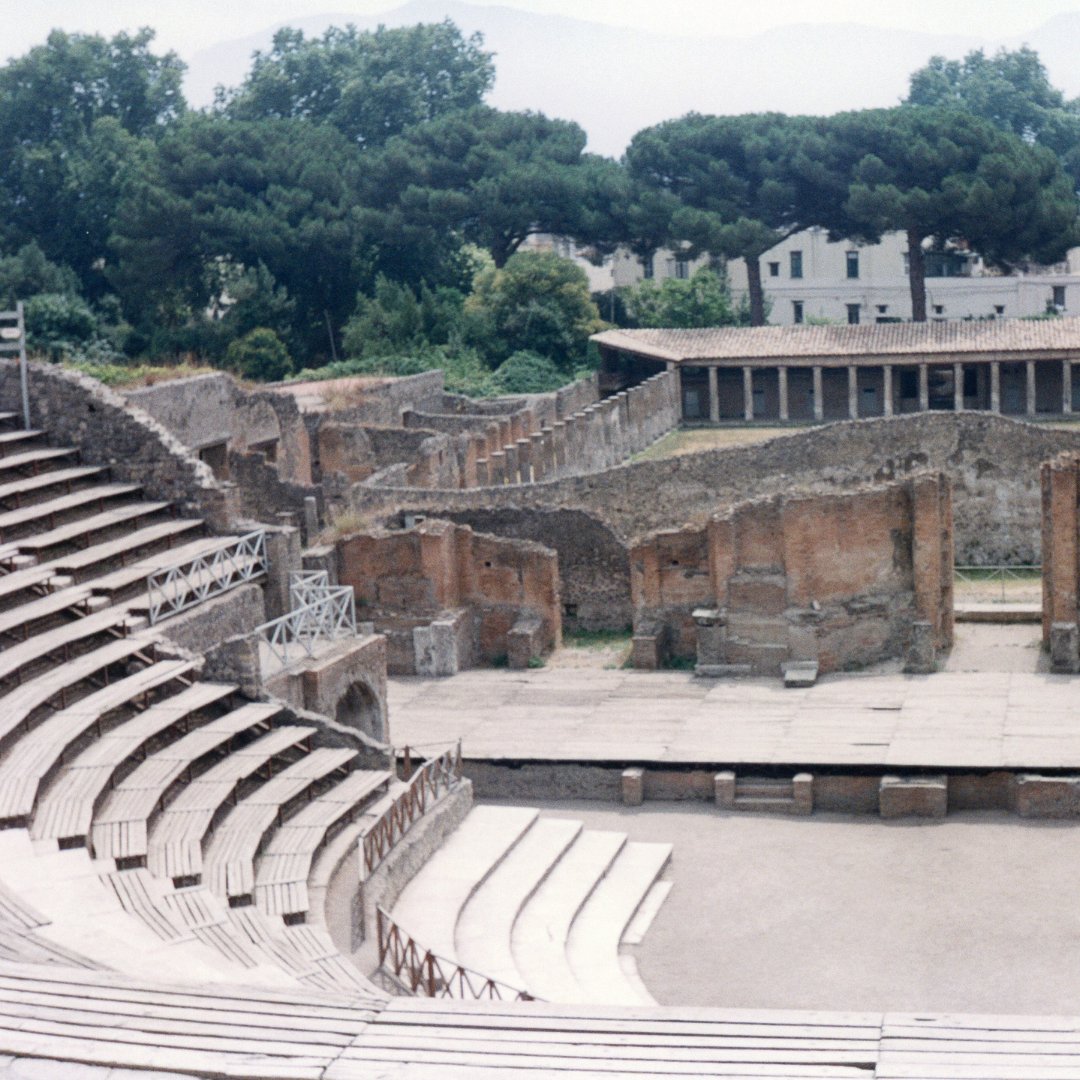 Il Teatro Grande di Pompei con le gradinate in pietra e i pini marittimi all'orizzonte